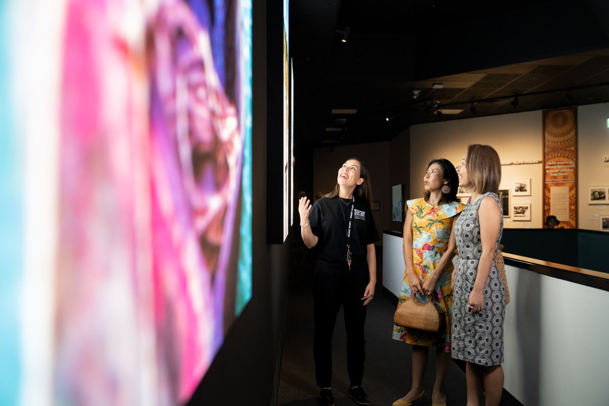 Museum employee and patrons admire wall art at Museum and Art Gallery NT in Darwin Northern Territory