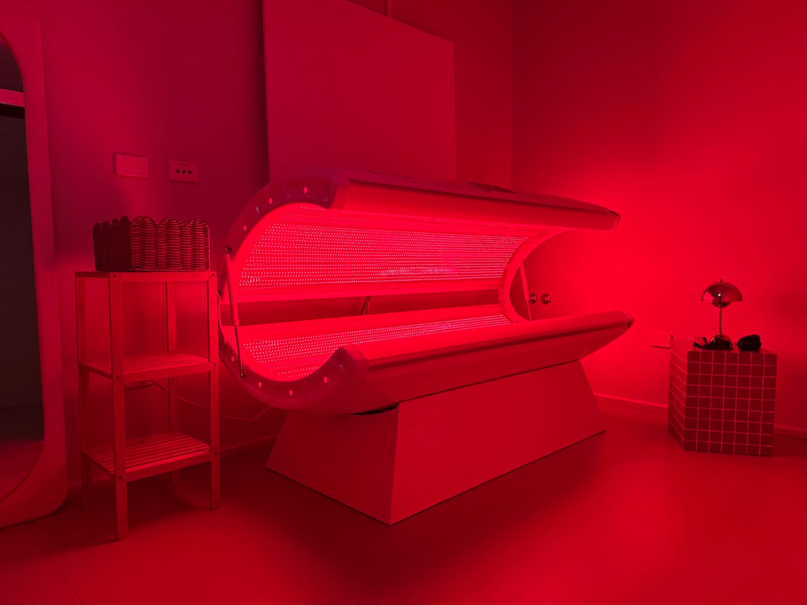 Red light therapy bed illuminated in a treatment room.