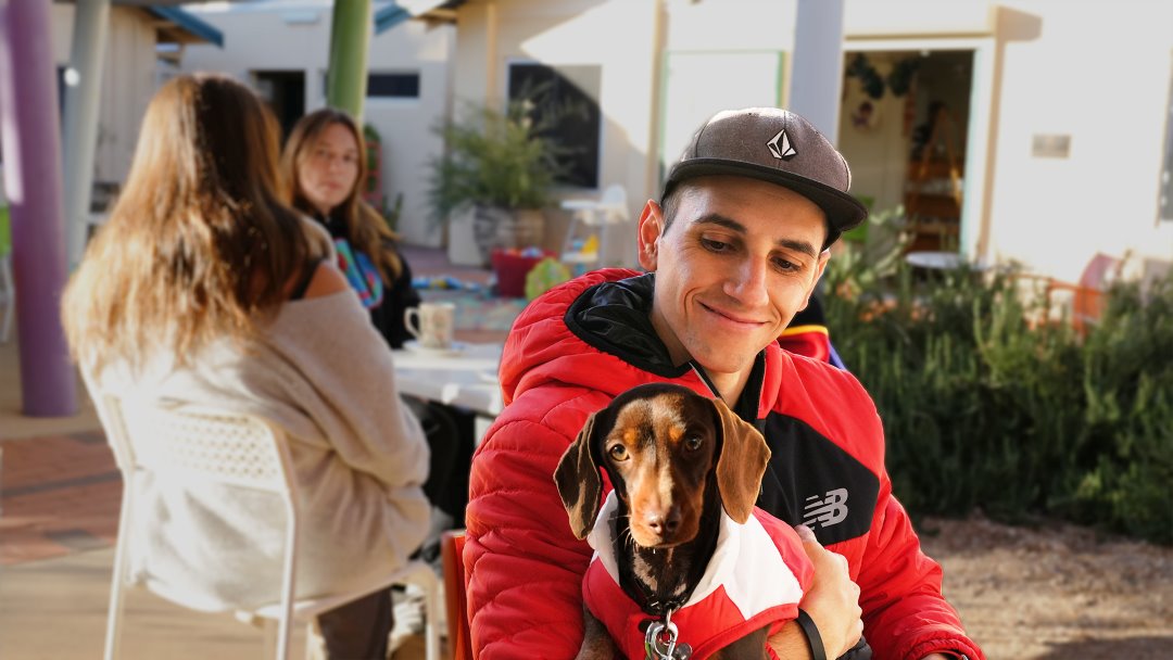 Man and dog wearing jumpers sitting at Yaye's Cafe in Alice Springs Northern Territory