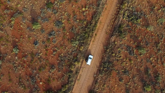 Aerial of vehicle driving through remote NT