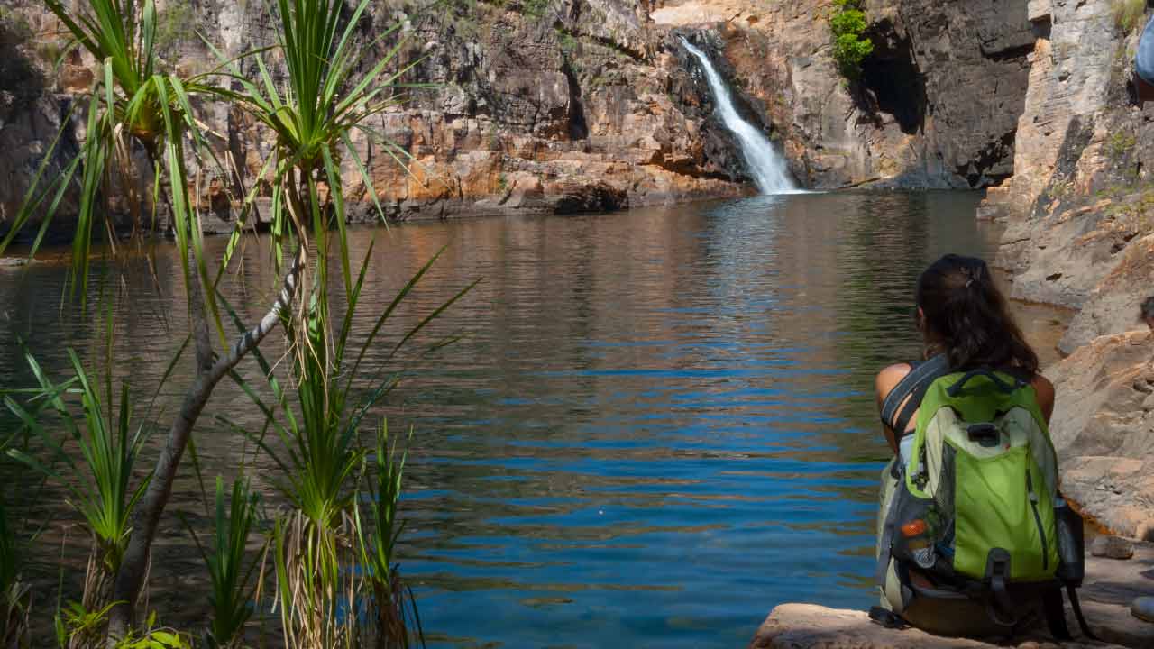 Woman with backpack sitting on rock at Maguk (Koolpin Gorge) in Kakadu, Northern Territory