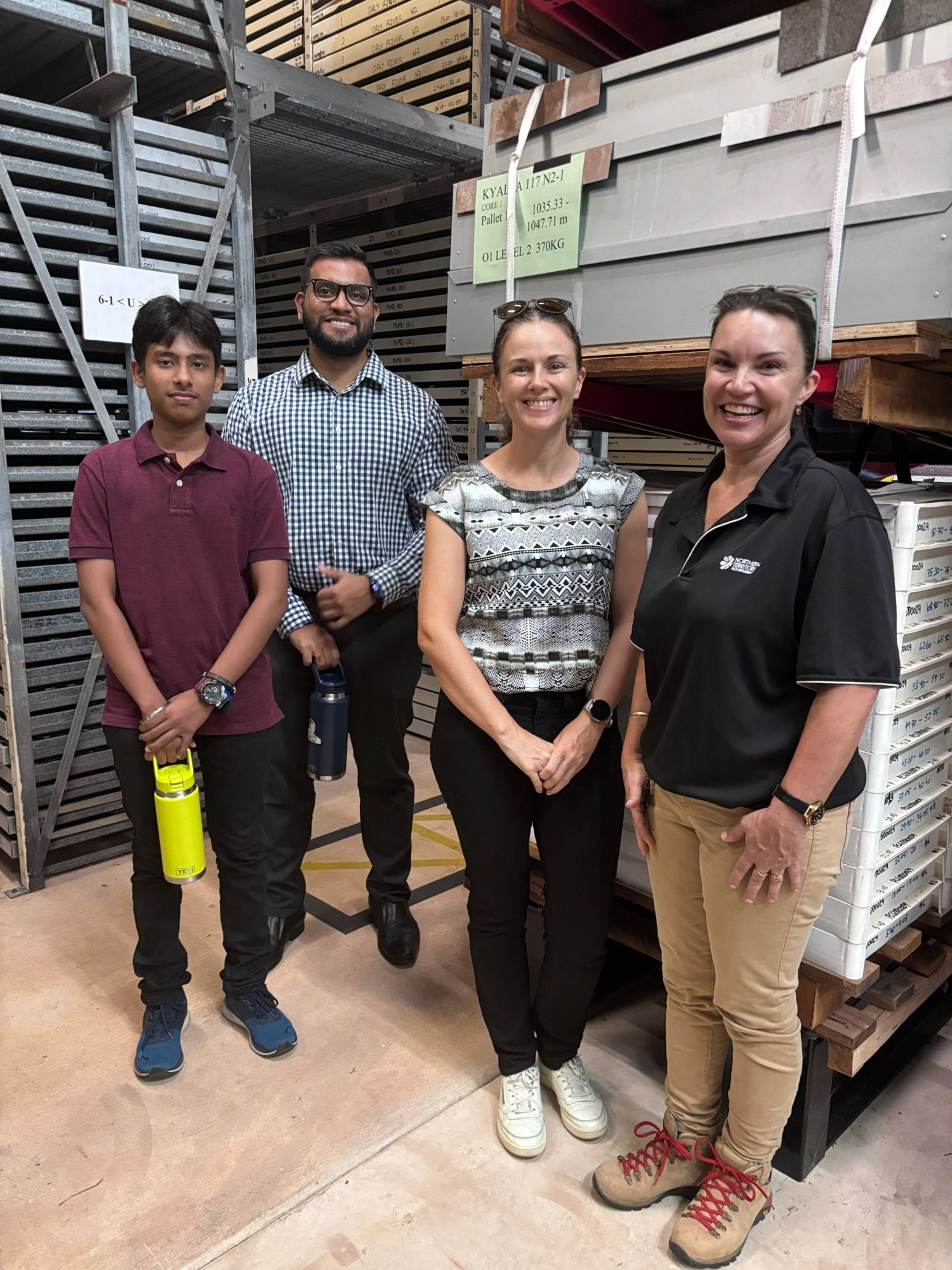 Four people standing in a warehouse among timber and building material storage racks, highlighting careers and workplace opportunities in the Northern Territory's construction and manufacturing industries.