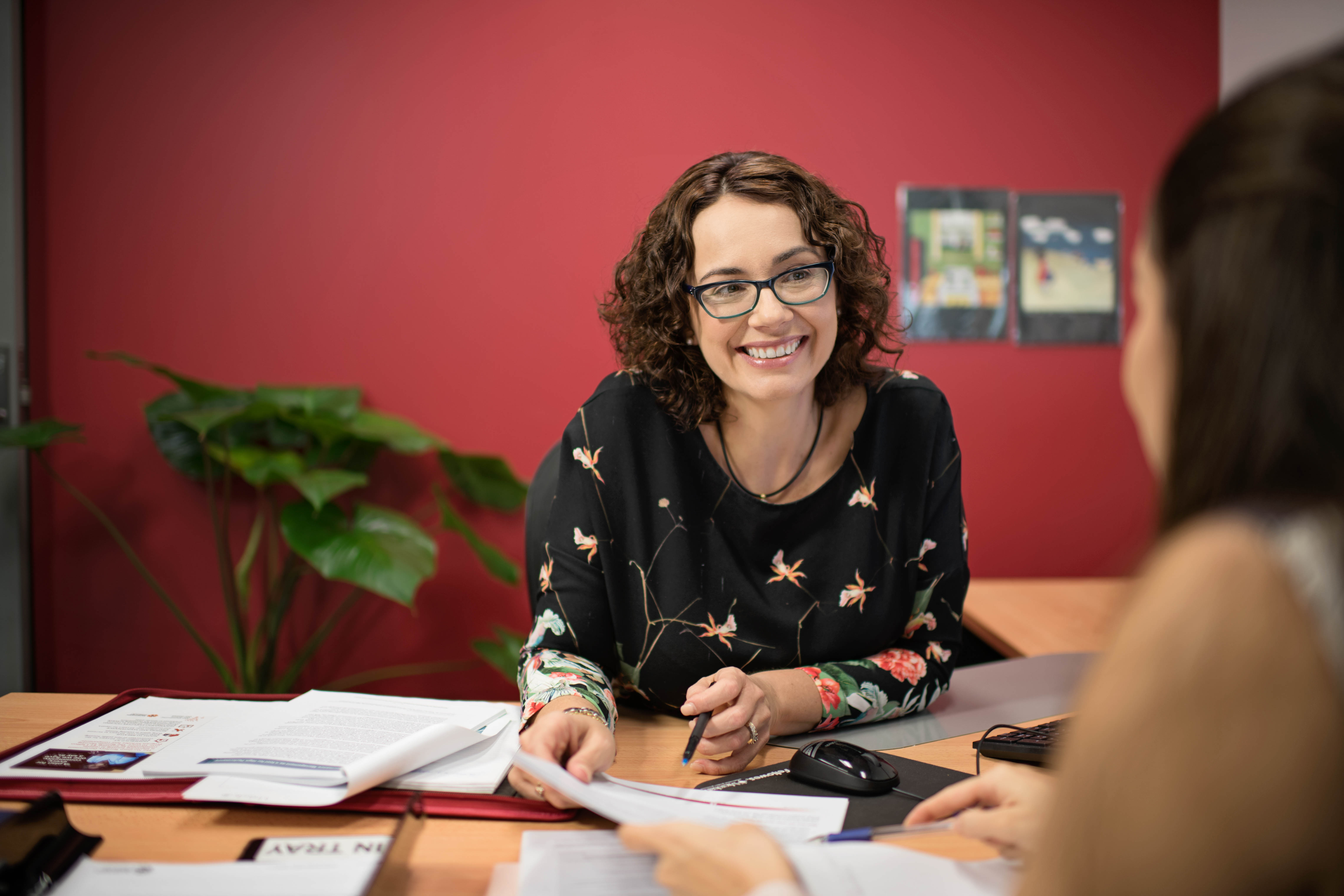 smiling woman at her desk helping a client